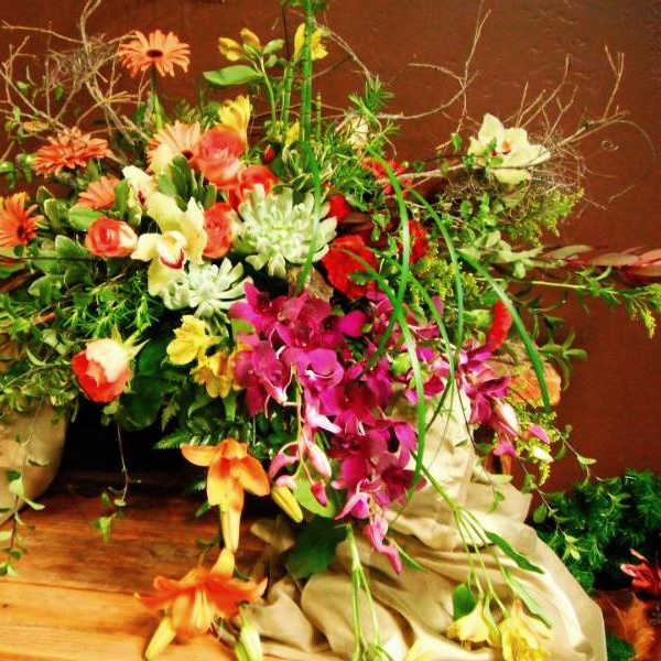 Large mixed floral arrangement with orchids and daisies in a low container