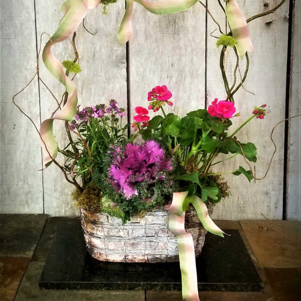 Basket arrangement with pink flowers and ribbon on a twig frame