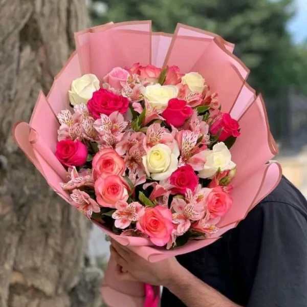 Bouquet of pink, white, and red roses wrapped in pink paper