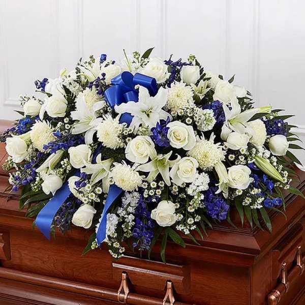 White and blue floral spray arranged on a wooden casket
