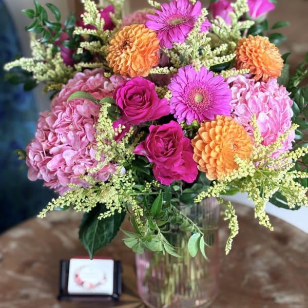 Bouquet of pink, orange, and purple flowers in a glass vase