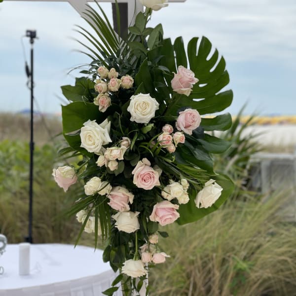 Tall floral arrangement with pink and white roses and large tropical leaves