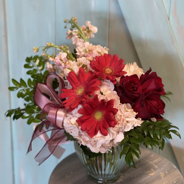 Bouquet of red roses and gerbera daisies in a glass vase