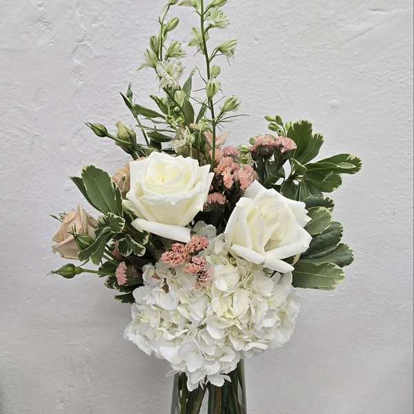 White roses and hydrangea in a clear glass vase with pink accents