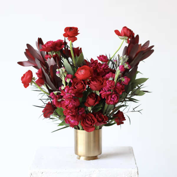 Red and pink floral arrangement in a gold vase