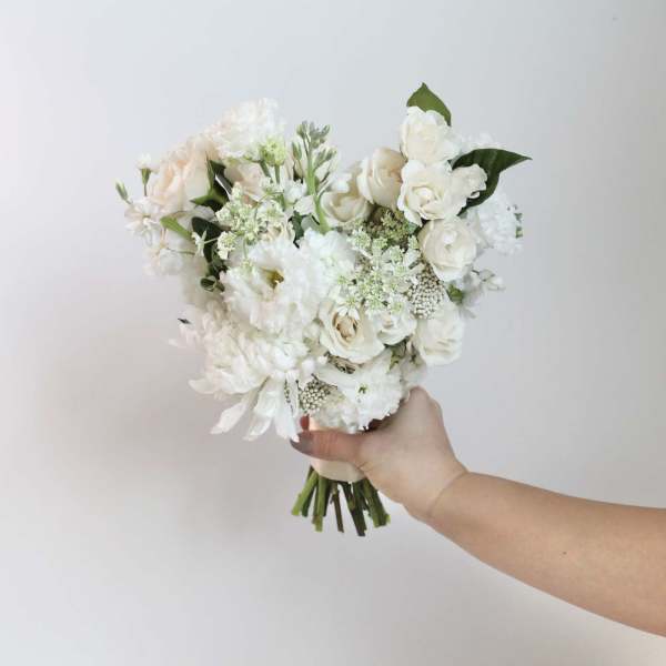 White and cream bouquet of roses and mixed blooms held in hand