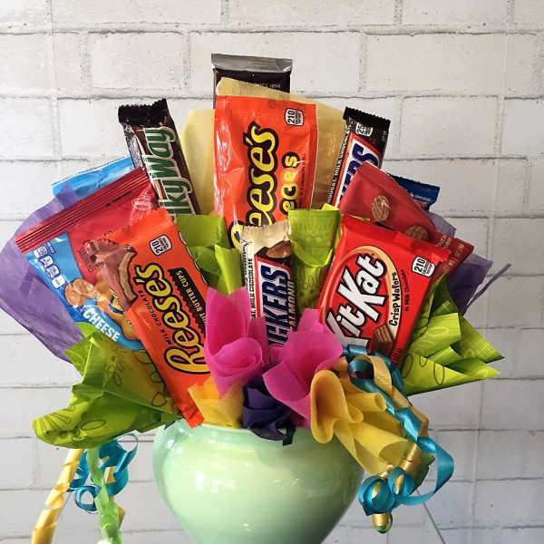Candy bouquet in a green vase with assorted chocolate bars and ribbons