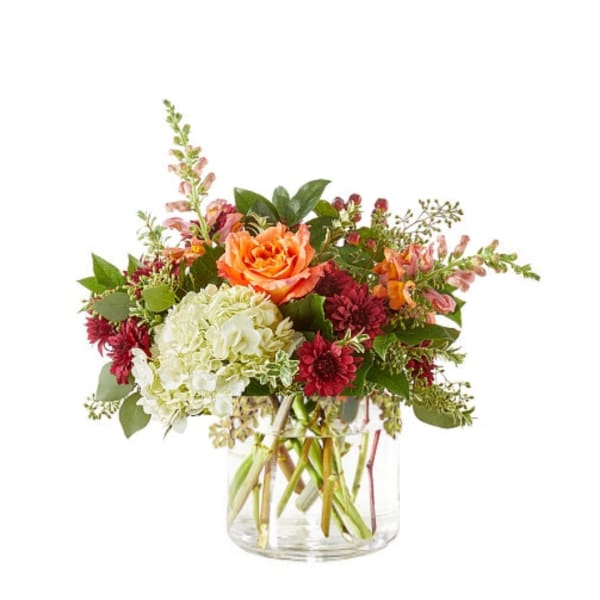 Mixed bouquet of orange, white, and burgundy flowers in a clear glass vase