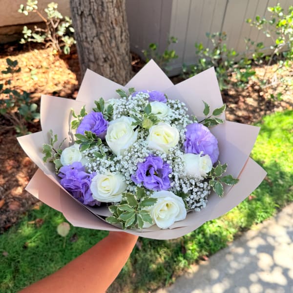Bouquet of white and lavender roses wrapped in pale paper