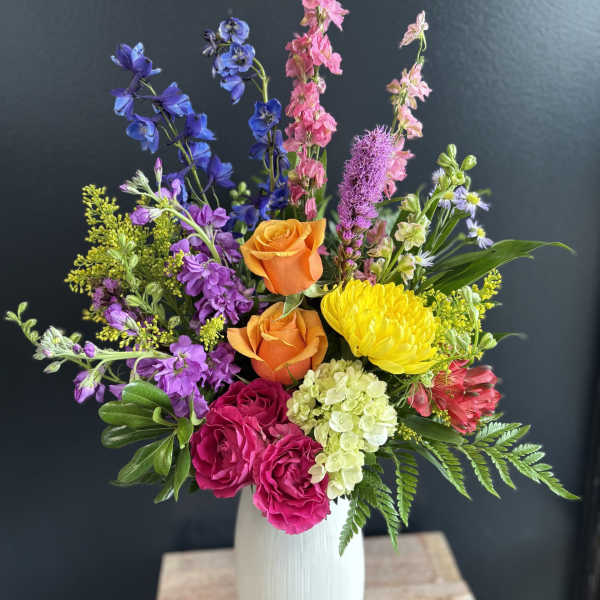 Colorful mixed bouquet in a white vase with roses and tall blooms