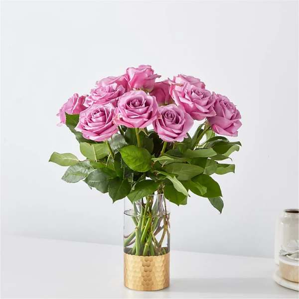 Pink roses arranged in a clear glass vase with a gold base