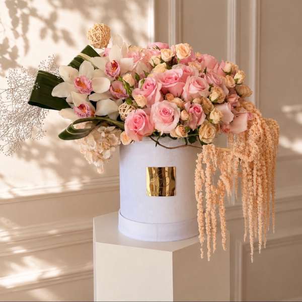 Pink roses and white orchids arranged in a white hat box