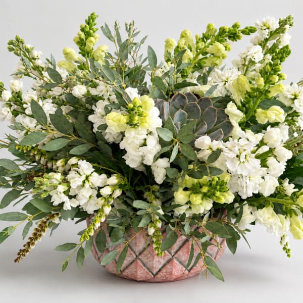 White and pale green floral arrangement in a pink textured vase
