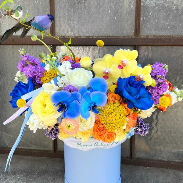 Bright mixed bouquet in a blue hatbox with a bird decoration