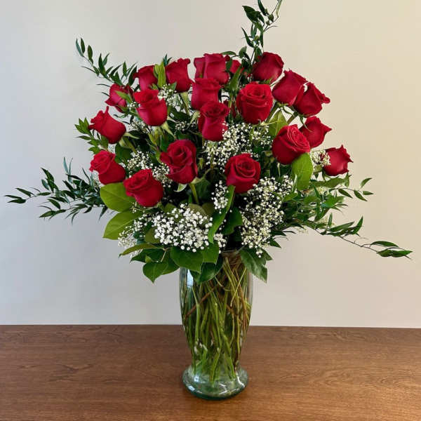 Red roses arranged in a clear glass vase with white filler flowers