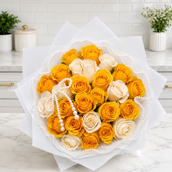 Bouquet of yellow and cream roses wrapped in white paper with pearl trim