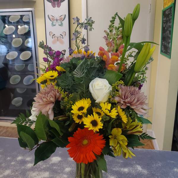 Mixed bouquet in a glass vase with lilies, roses, daisies, and chrysanthemums