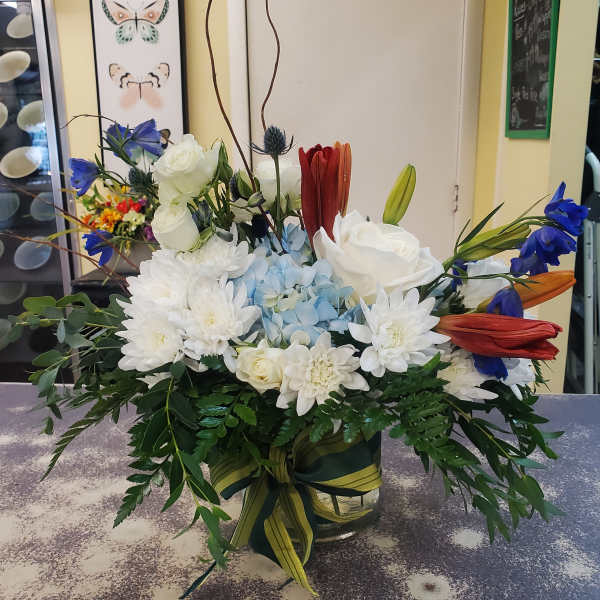 Mixed bouquet in a glass vase with white, blue, and red flowers