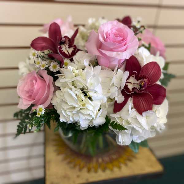 Pink roses and white hydrangeas with burgundy orchids in a glass vase