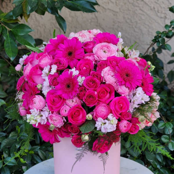 Pink bouquet of roses, ranunculus, and gerbera daisies in a pale pink box