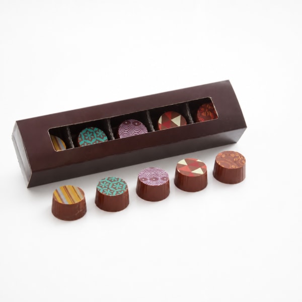 Box of assorted chocolates with patterned tops on a white background