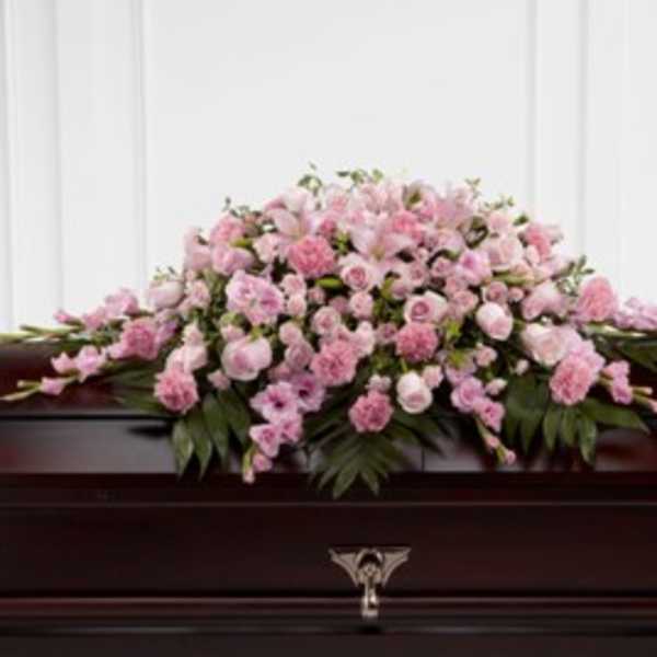 Pink floral casket spray on a dark wooden casket