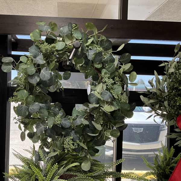Large green wreath with round leaves hanging in a window display