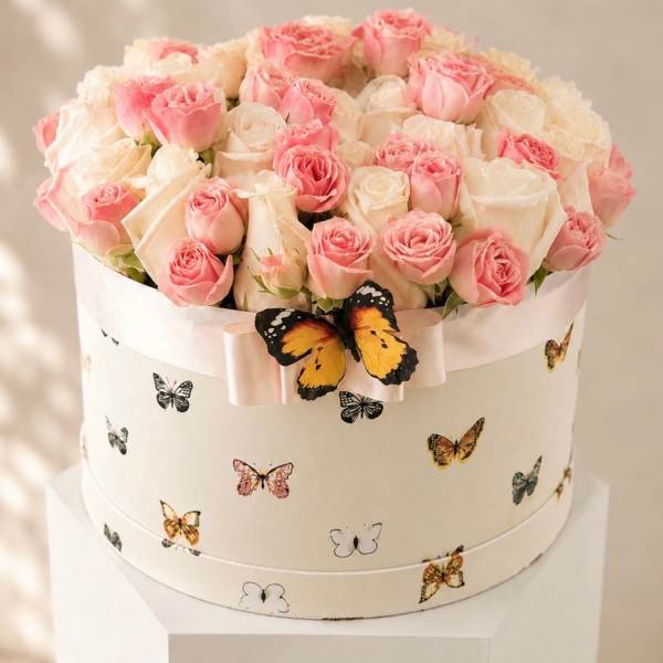 Pink and white roses in a round hat box with butterfly decorations