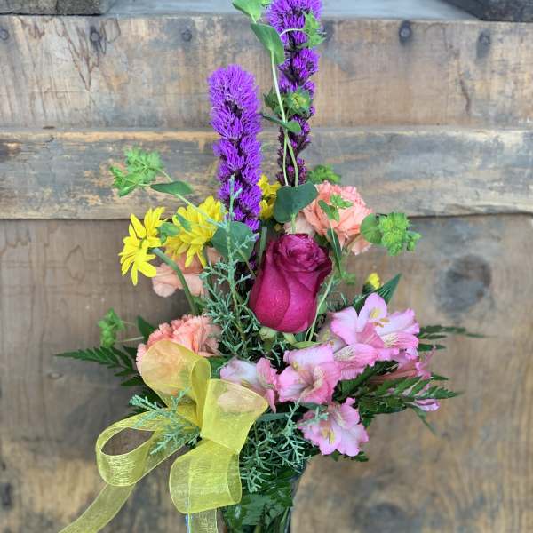 Mixed bouquet in a glass vase with pink, purple, and yellow flowers
