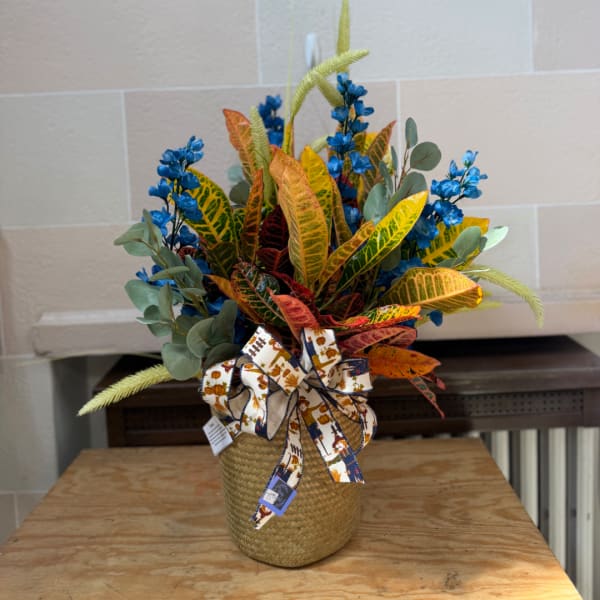 Colorful floral arrangement in a woven basket with a decorative ribbon