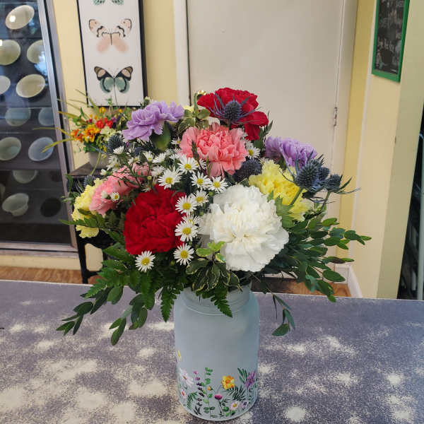 Mixed bouquet of carnations and daisies in a painted metal vase