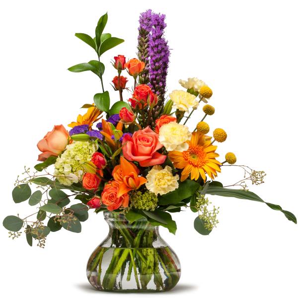 Mixed bouquet of roses, lilies, carnations, and purple spikes in a glass vase