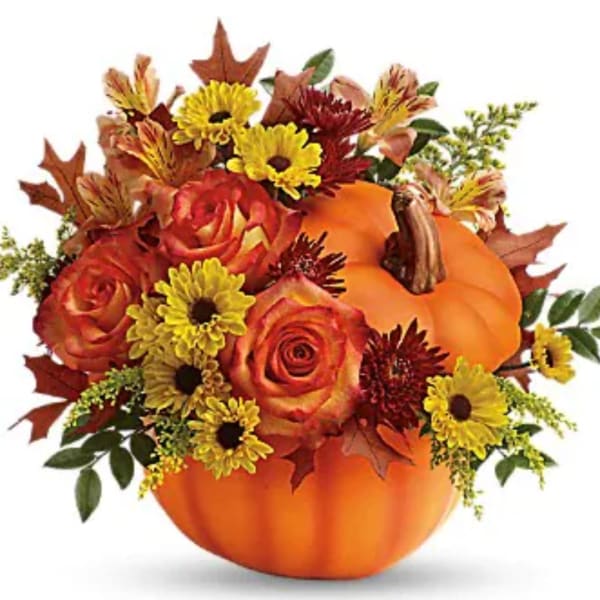 Fall floral arrangement in a pumpkin container with roses and daisies
