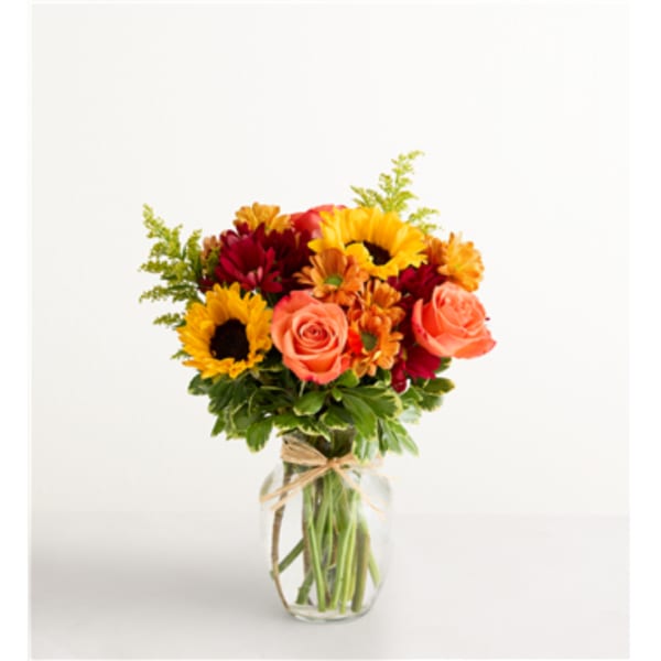 Bouquet of sunflowers, roses, and daisies in a glass vase