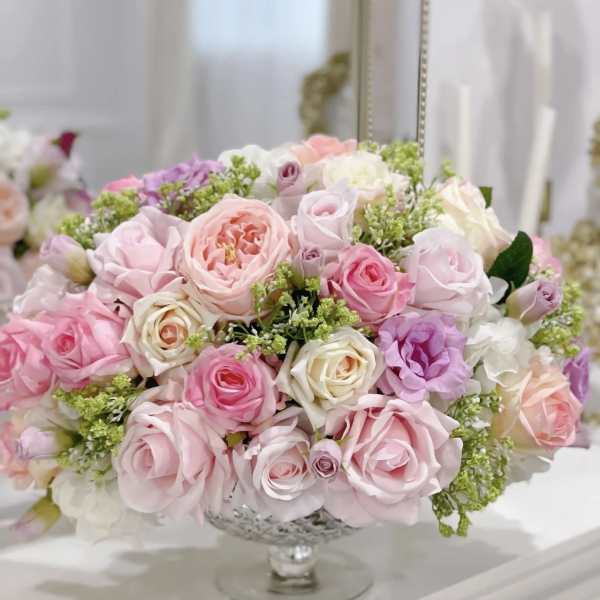 A pastel rose arrangement in a glass pedestal vase