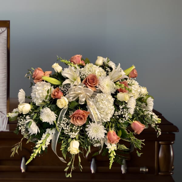 Large floral spray with pink and white roses in front of a casket