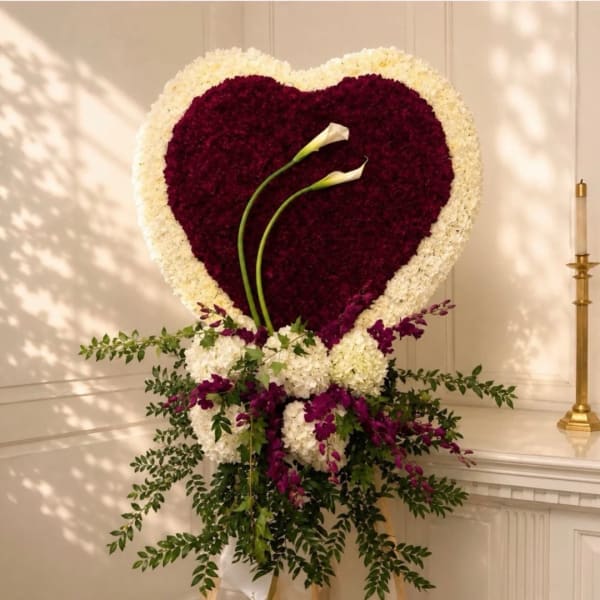 Heart-shaped floral arrangement with two white calla lilies and purple and white flowers