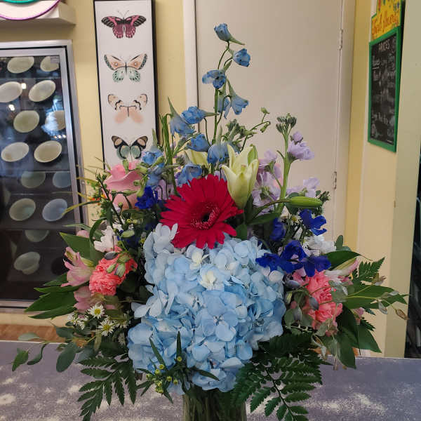 Colorful mixed bouquet with blue hydrangea, gerbera daisy, lilies, and pink flowers in a vase