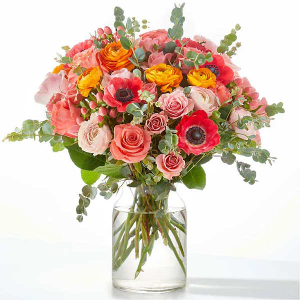Bouquet of pink, coral, and yellow flowers in a clear glass vase