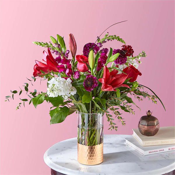 Mixed bouquet of red and purple flowers in a clear glass vase