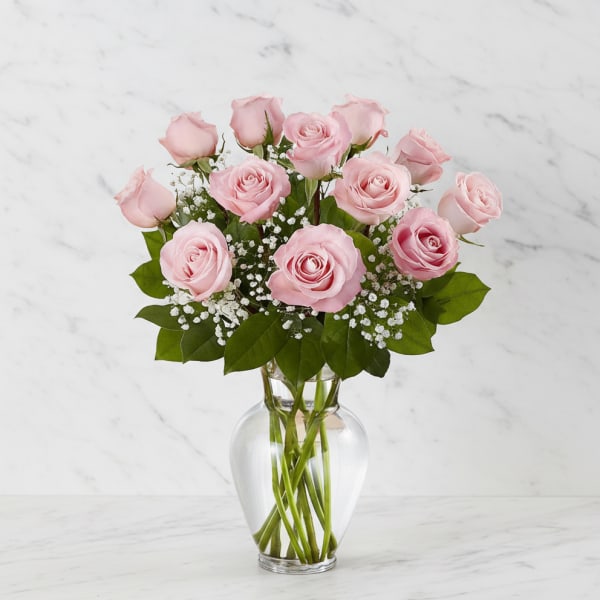Pink roses arranged in a clear glass vase with baby's breath