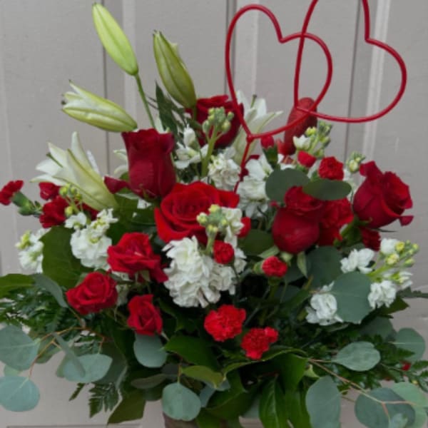 Red roses and white lilies in a tall vase with a red heart topper