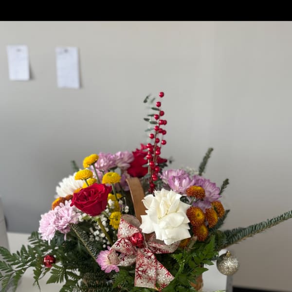 Basket arrangement with red and white flowers and a holiday ribbon