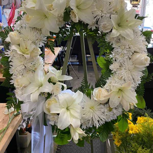 White floral wreath with lilies, roses, and chrysanthemums on an easel