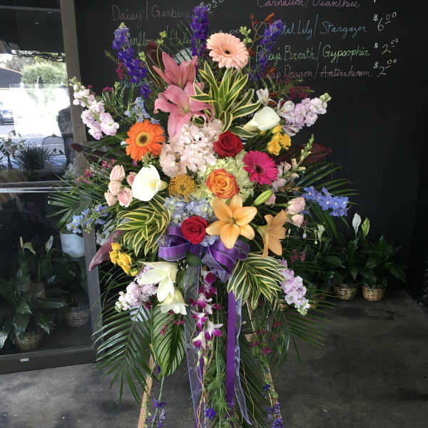 Tall standing floral spray with lilies, roses, gerberas, and orchids