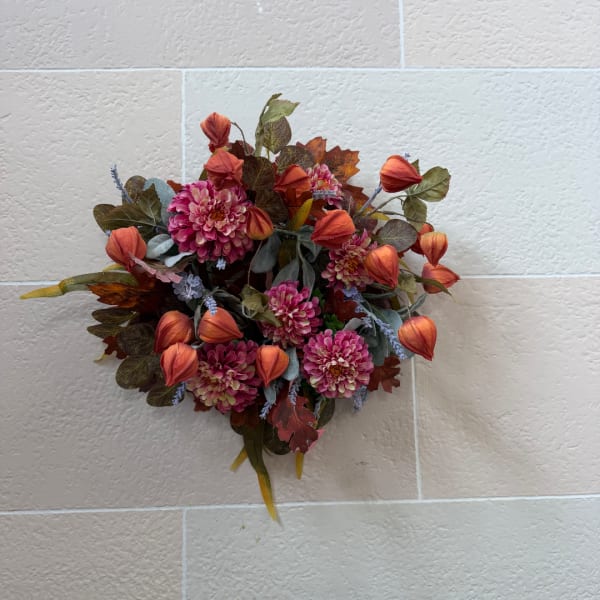 Wall-mounted floral arrangement with pink blooms and orange buds