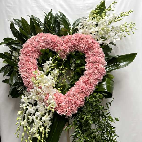 Heart-shaped pink carnation wreath with white orchids and greenery