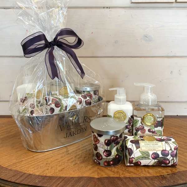 Cherry-themed bath and body gift set in a metal tub wrapped in cellophane with a dark ribbon bow