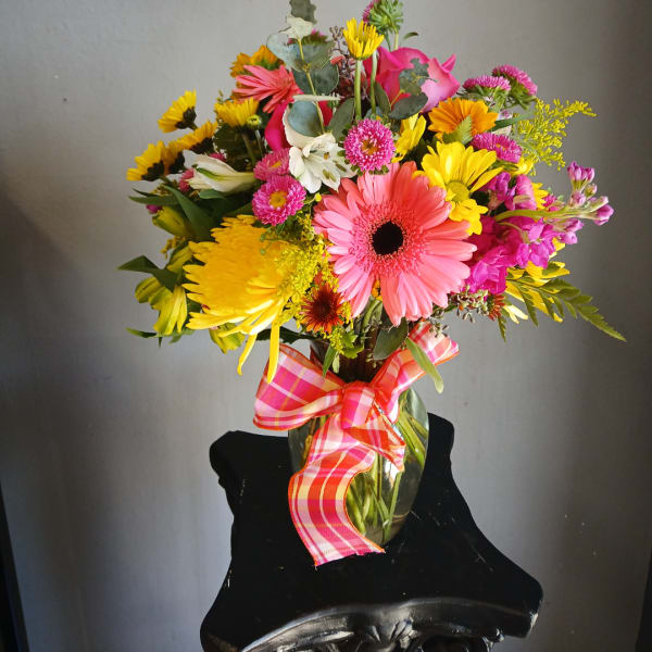 Colorful mixed bouquet in a glass vase with a pink plaid ribbon
