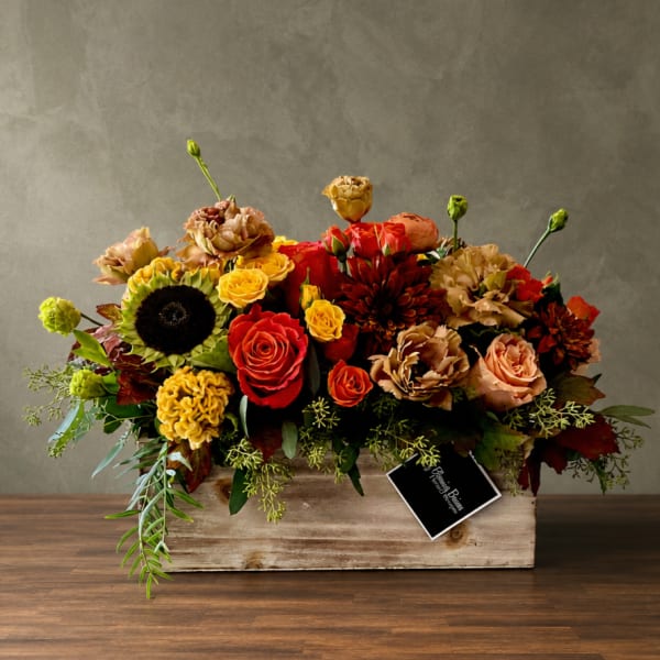 Mixed bouquet of red, yellow, and peach flowers in a wooden box